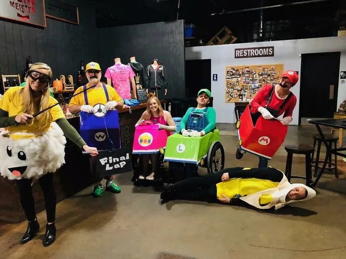 Group of creative people with disabilities in Mario Kart wheelchair costumes celebrating Halloween.