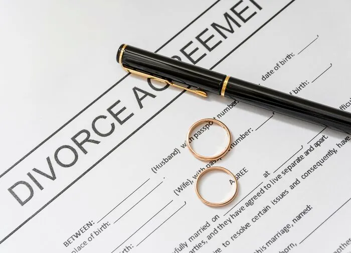 A divorce agreement document with two wedding rings and a black pen