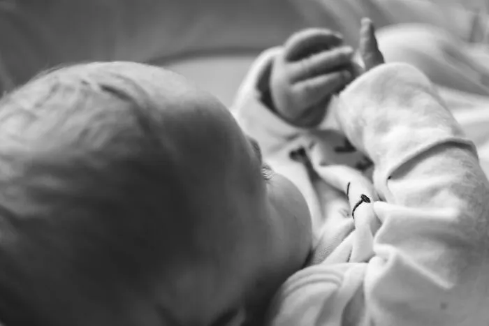 Close-up of a baby's face and hand in black and white photo of patients