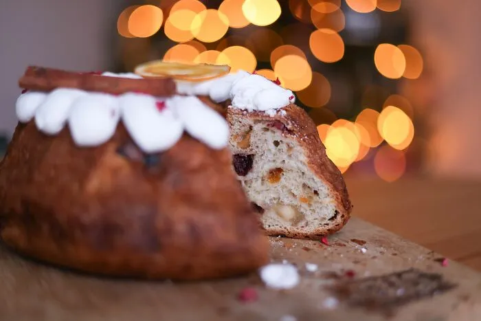 Close-up of decorated sweet bread with icing and fruit pieces on wooden surface