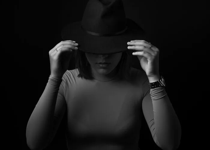 Woman adjusting hat on her head in black and white photo highlighting personal expression