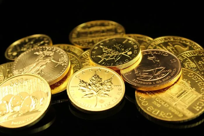 Pile of gold coins including Canada gold coins on black surface