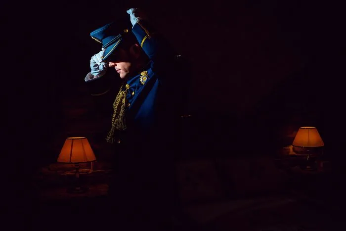 Person in military uniform adjusting hat in dim room light