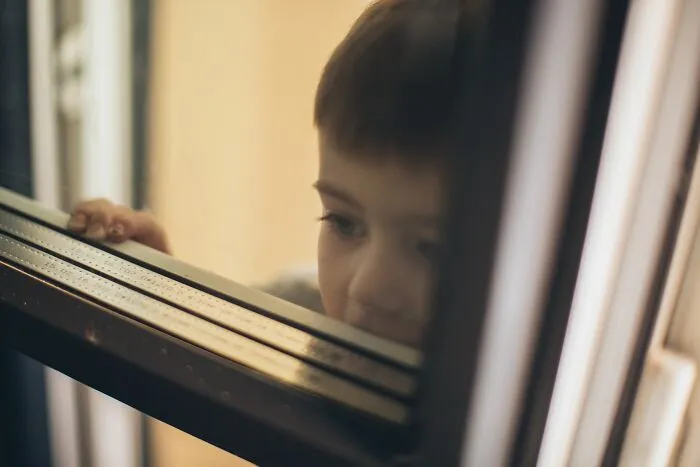 Sad young boy staring out window symbolizing patients with little time left