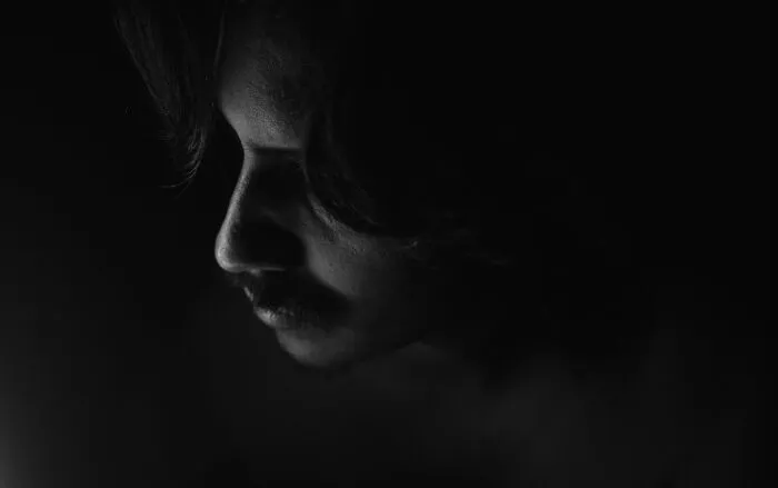 Black and white close-up portrait of a man looking down thoughtfully