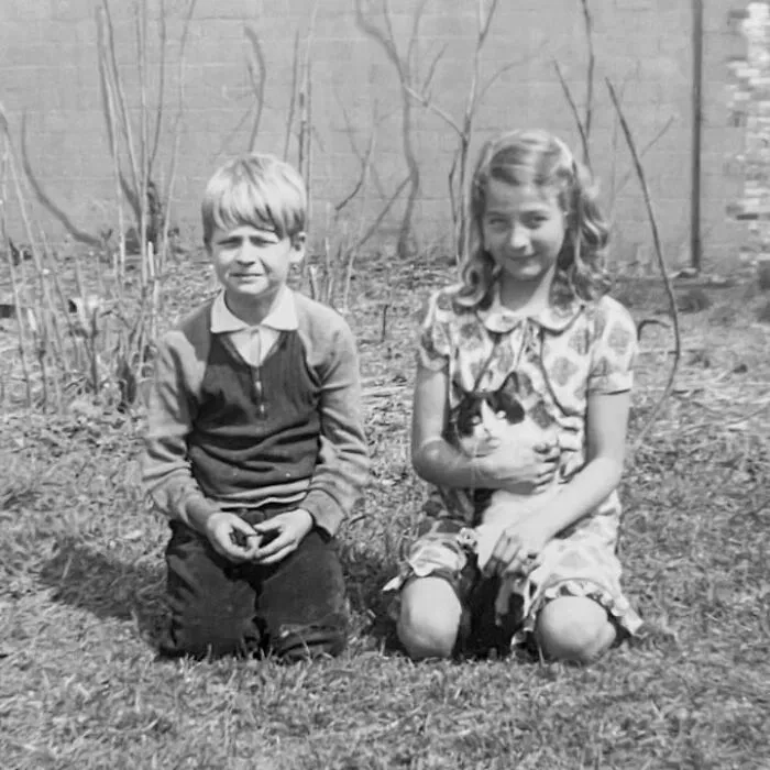 Two kids kneeling on the grass with a cat in vintage photos of children with their cats
