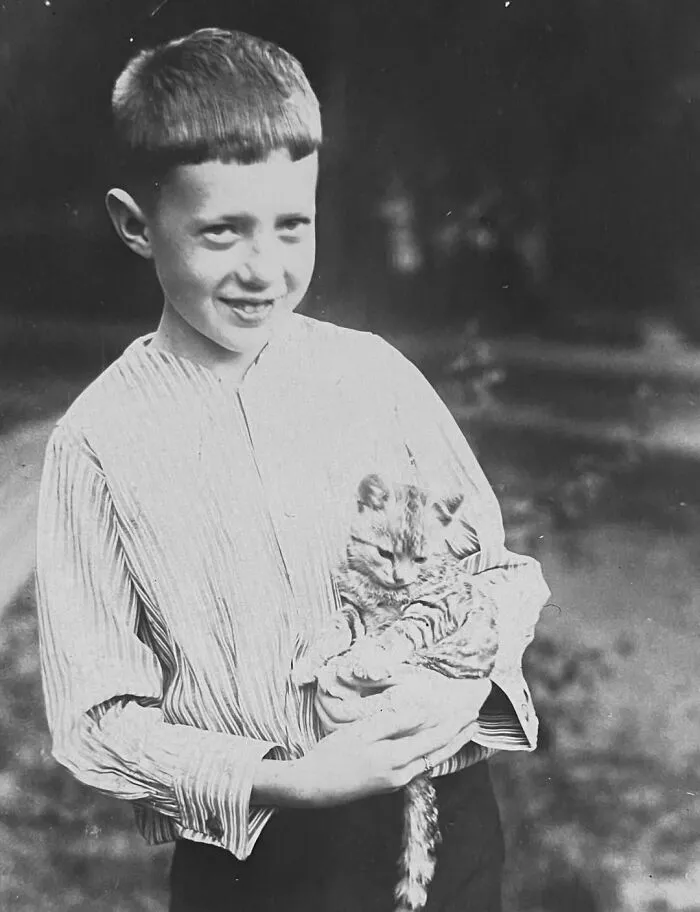 A smiling boy holding a small tabby kitten, showing vintage photos of children with their cats