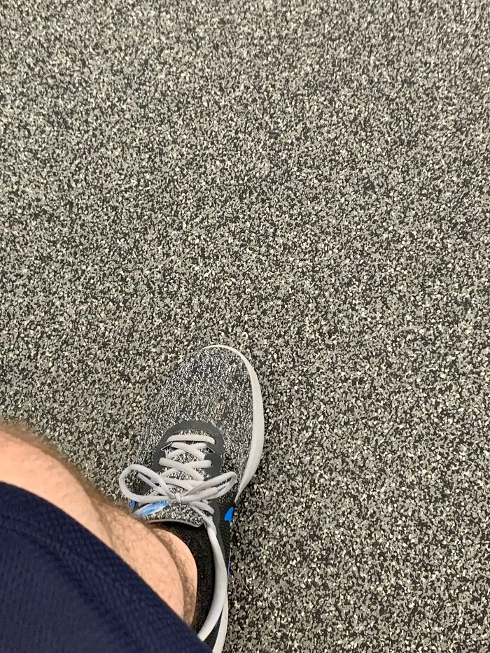 A perfectly confusing photo of a sneaker blending seamlessly into the speckled carpet pattern below it.