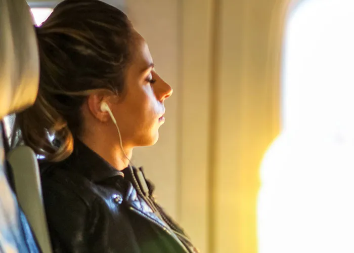 Passenger listening to music with earphones in airplane seat