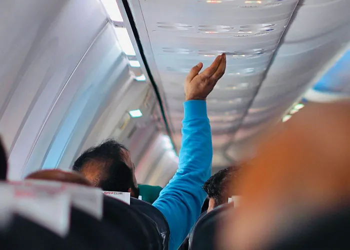 Passenger reaching for overhead bin on a crowded airplane