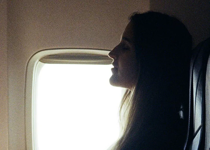 Passenger looking out airplane window on flight amid entitled passenger