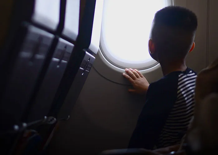 Child looking out airplane window at 30000 feet flight view