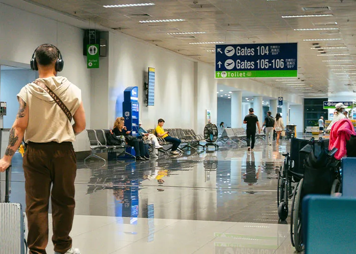 Traveler walking in airport terminal near gates and toilet signs