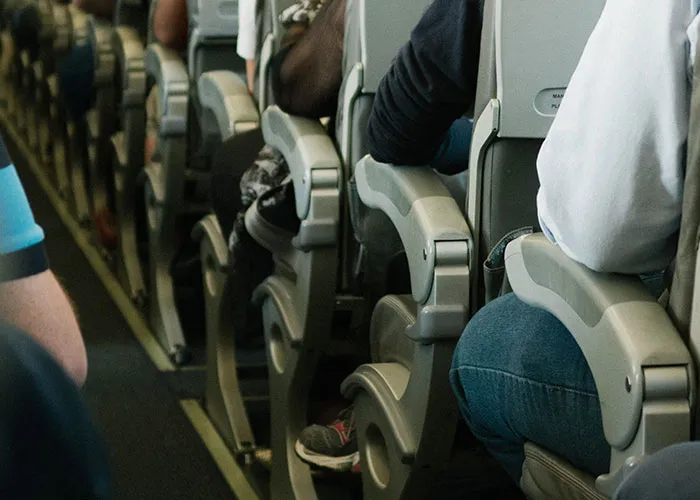 View of airplane seats with passengers seated closely together