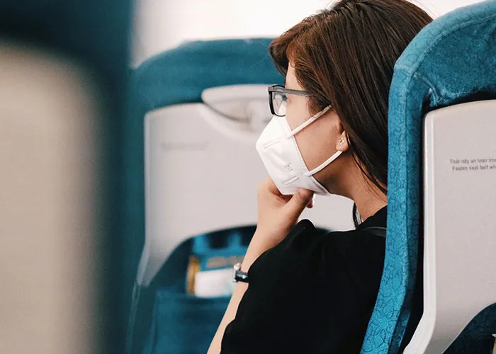 Passenger wearing mask sitting inside airplane cabin