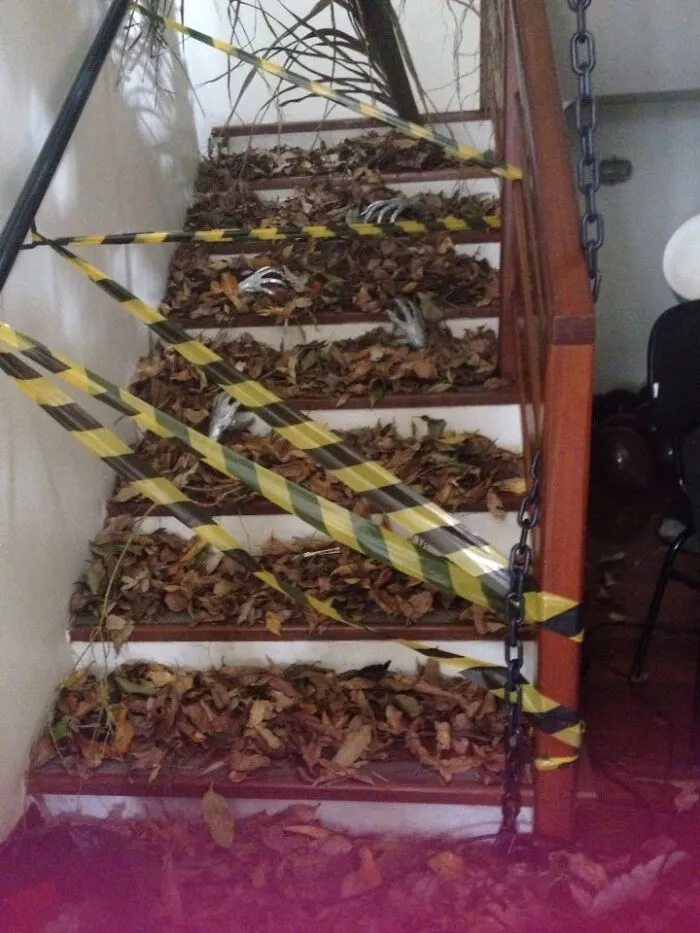 Stairs covered in autumn leaves, skeleton hands, and caution tape for a Halloween haunted house look.