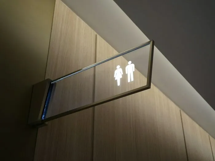 A modern public restroom sign on a wooden wall, representing everyday normal life