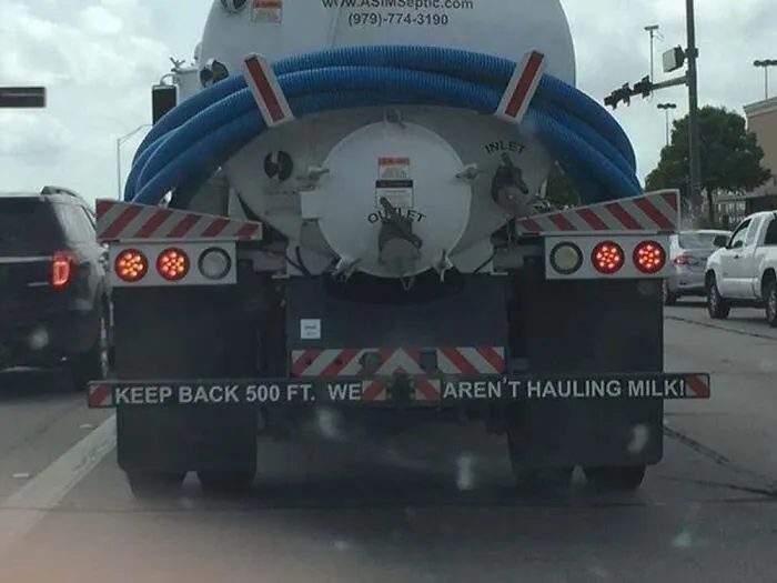 Septic truck with funny text on bumper saying WE ARENT HAULING MILK showing truckers humor.