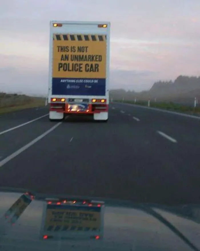 Rear of a truck turned into a moving joke with sign reading THIS IS NOT AN UNMARKED POLICE CAR on the road.