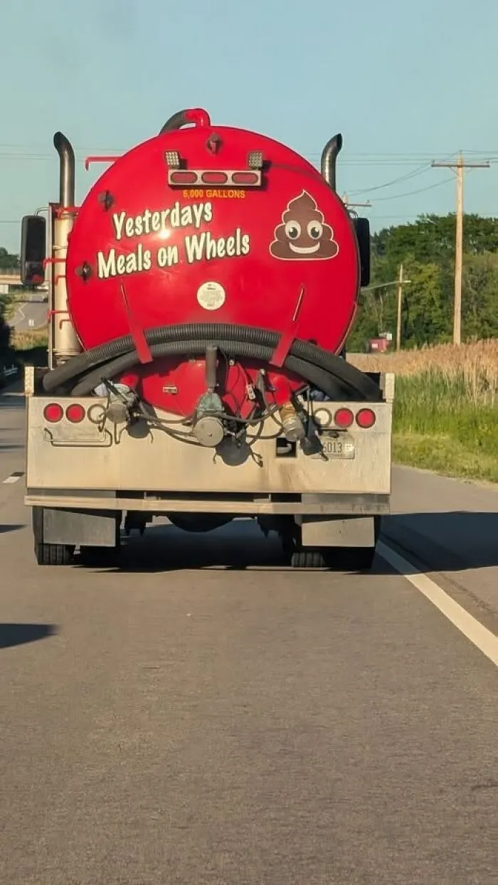 Rear of a red sewage tanker truck with funny Yesterdays Meals on Wheels text.