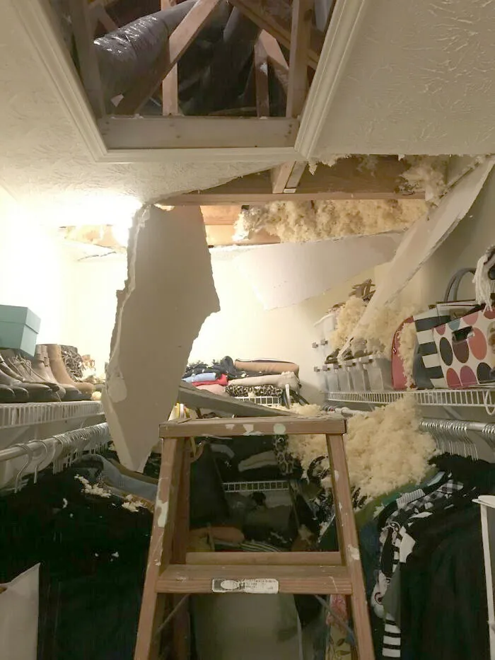 A collapsed drywall ceiling inside a closet, depicting a home renovation disaster with insulation everywhere.