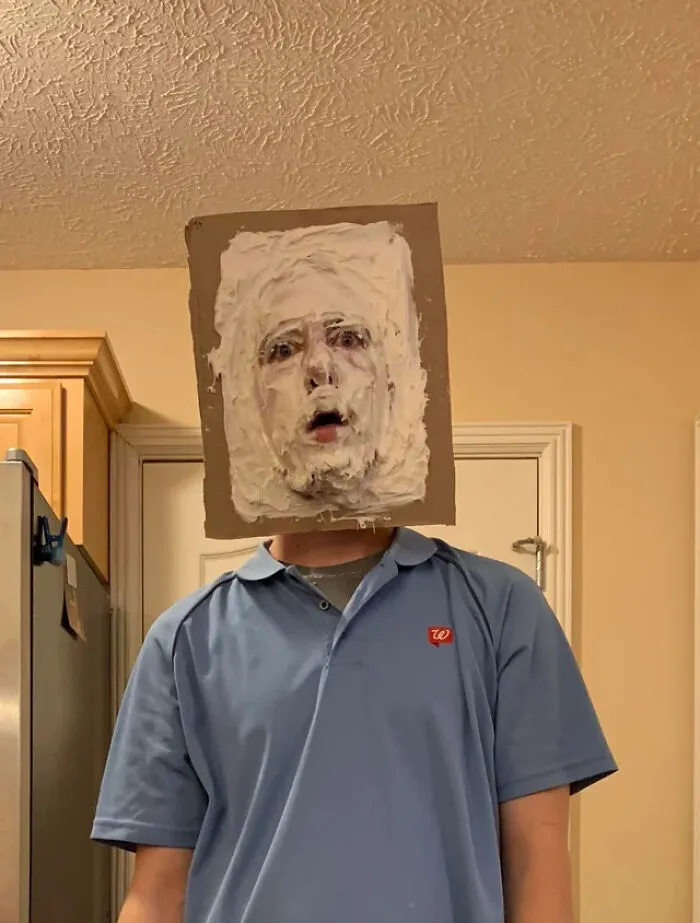 A person with a face covered in white cream framed by cardboard as a creative Halloween costume idea.