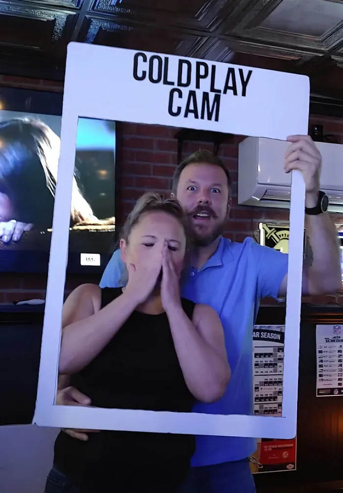 Couple posing behind a Coldplay Cam frame for fun Halloween costume ideas.