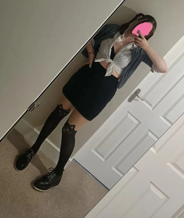 A woman taking a mirror selfie in a cute schoolgirl Halloween costume.
