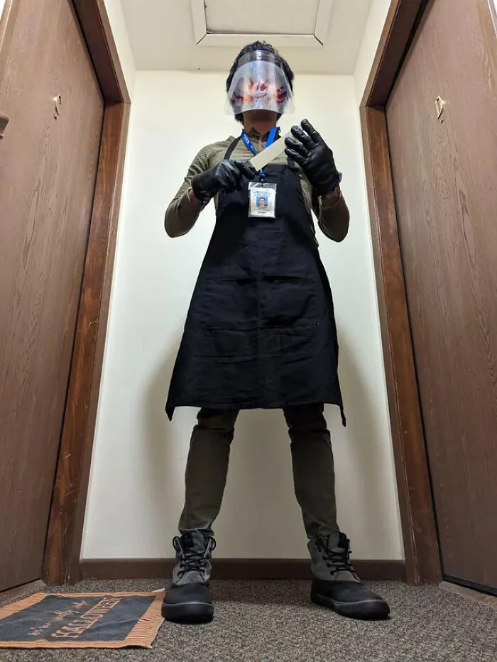A person dressed as Dexter with a face shield and apron for a spooky Halloween costume.