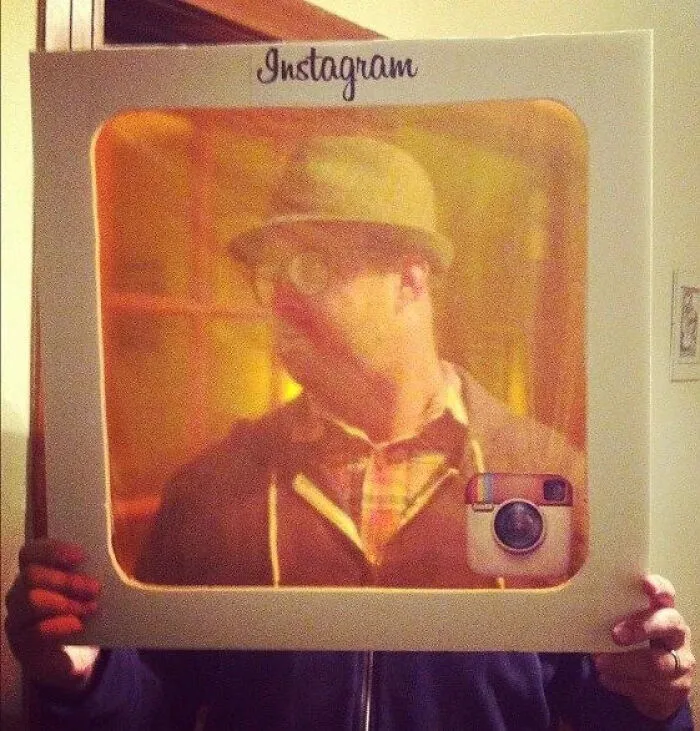 A person holding an Instagram photo frame cutout for a simple Halloween costume idea.