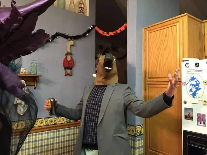 Man wearing a suit and a horse head mask as a funny Halloween costume idea at a party.