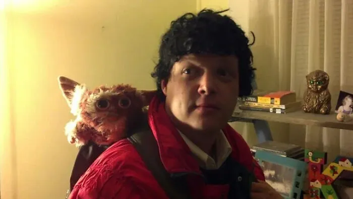 A man with a Gizmo plush toy on his shoulder in a funny Halloween costume idea.