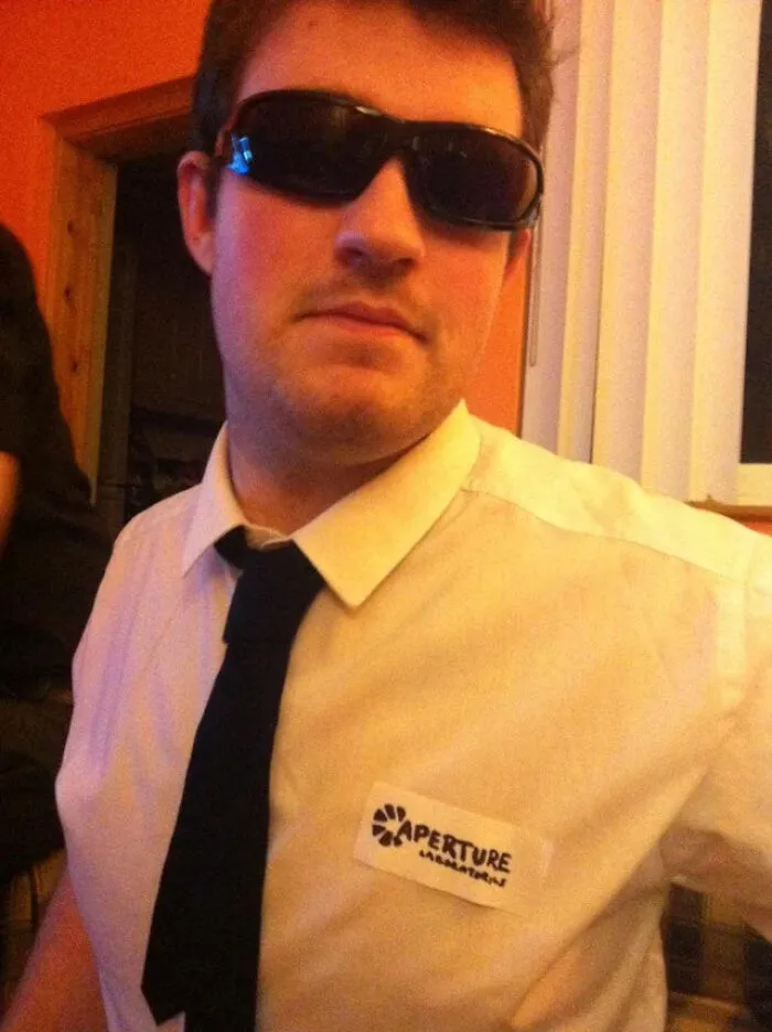 Man wearing sunglasses and a white shirt with an Aperture Laboratories badge for a cool Halloween costume idea.