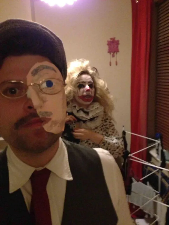 Man wearing half face cutout with a clown in background showing creative Halloween costume ideas