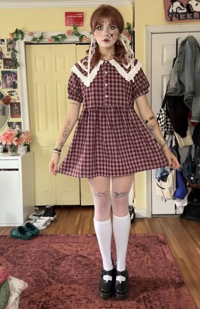 Woman posing in a vintage plaid dress and doll makeup, a creative Halloween costume idea
