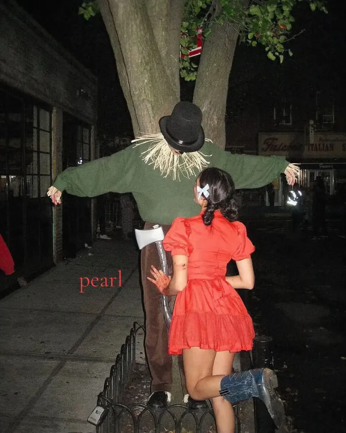 Woman in red dress posing next to a scarecrow, inspired by Pearl for a Halloween costume idea