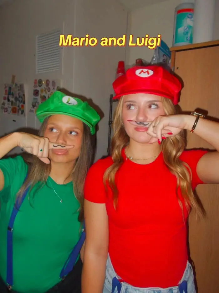 Two friends posing in red and green shirts with matching hats as a Mario and Luigi Halloween costume.