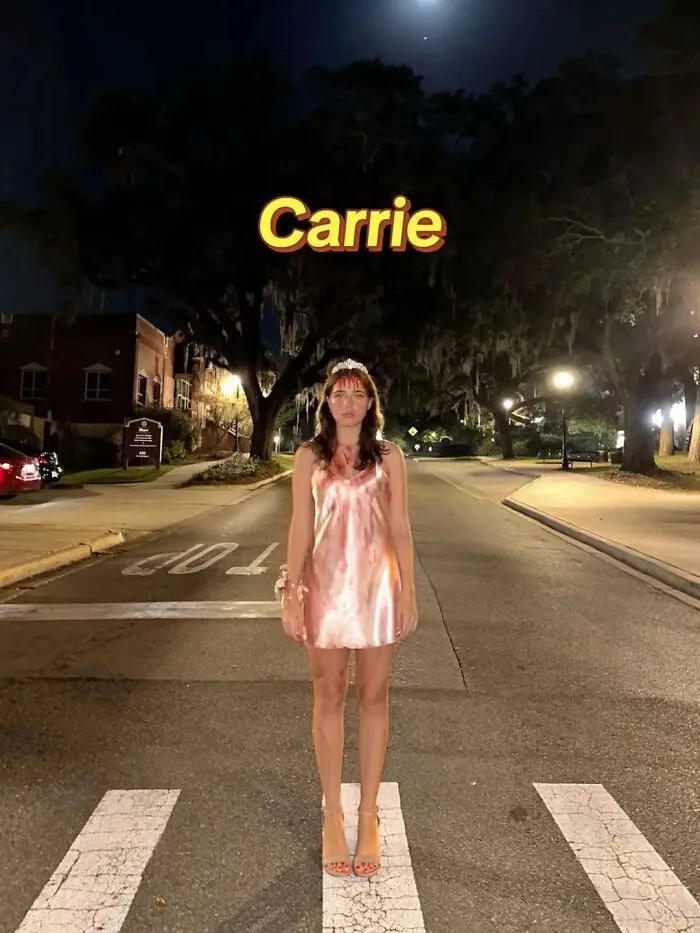 A woman posing in a blood-stained dress and tiara as a Carrie Halloween costume idea.