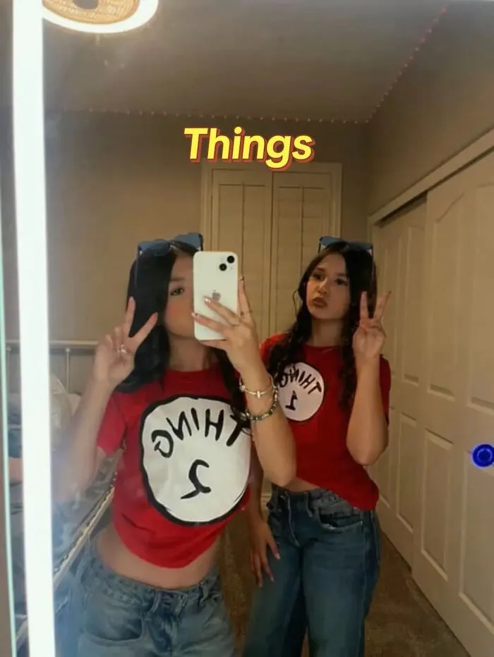 Two girls posing in matching red shirts as a Thing 1 and Thing 2 Halloween costume idea.