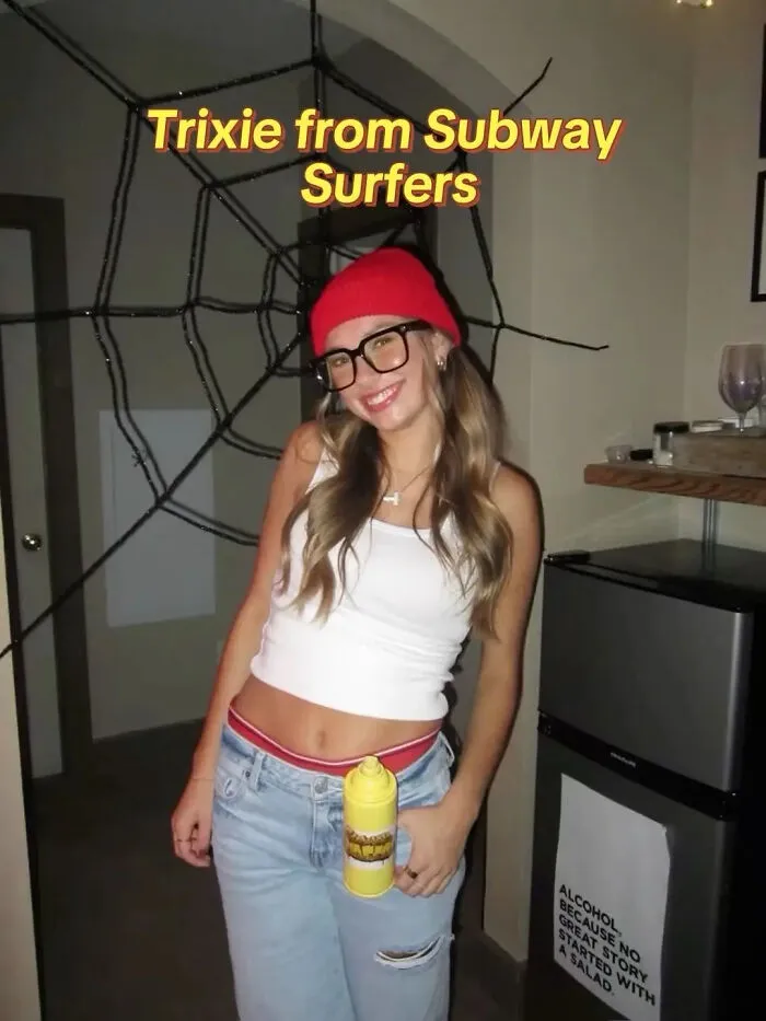 A woman wearing a red beanie and glasses as a Trixie Halloween costume idea.