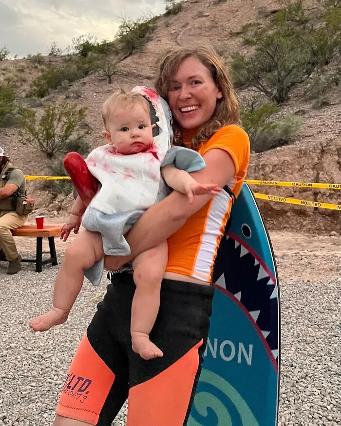 A woman holding a baby in a shark costume, showcasing creative Halloween ideas for people with disabilities.