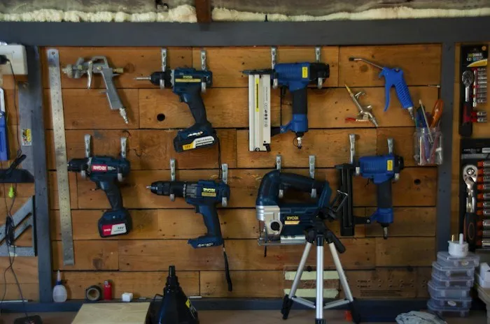 Power tools neatly mounted on a wooden pegboard wall, illustrating valuable dumpster finds.