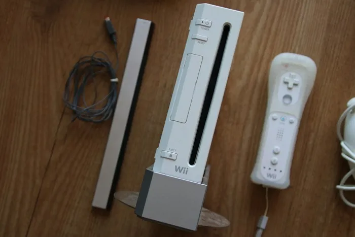 A white Nintendo Wii console with a controller and sensor bar, showing lucky dumpster finds on a wooden floor.