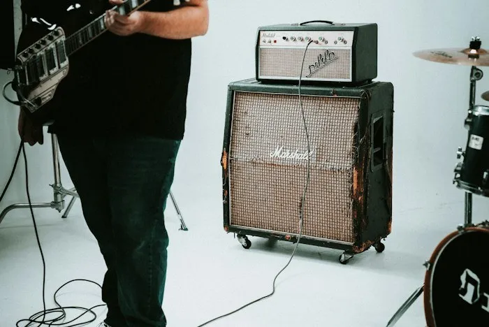 Musician playing guitar near vintage amp, showcasing unique dumpster finds.