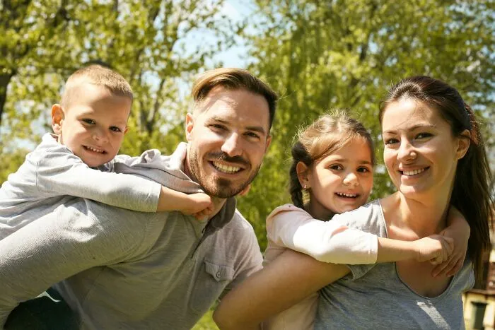 Happy family with children outdoors, unaware of hidden infidelity stories.