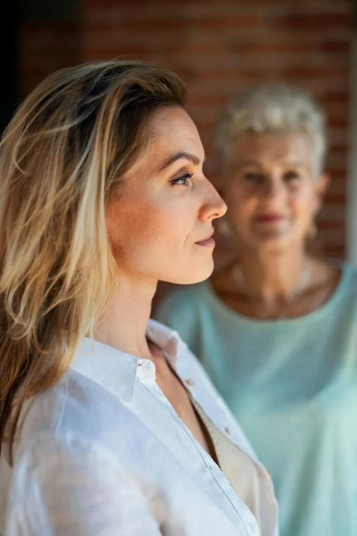 Side profile of a young woman with an older woman behind her, linked to infuriating family stories.