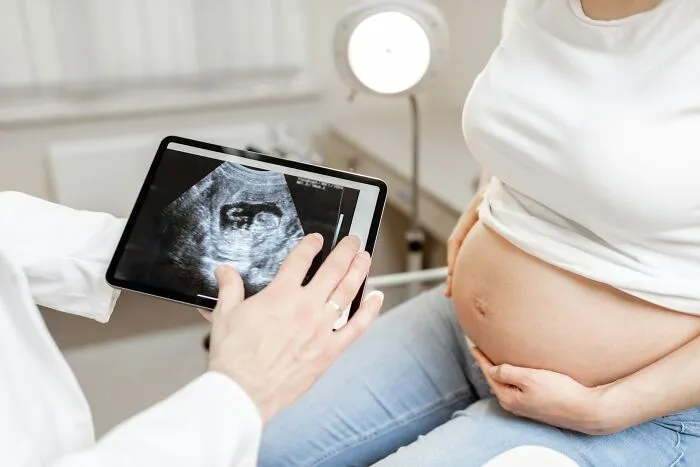 A doctor showing an ultrasound scan on a tablet to a pregnant woman, related to misunderstandings of women's bodies.