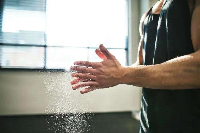 Close-up of an athlete clapping chalked hands before a workout, showcasing practical everyday life fitness tips
