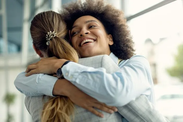 Two women sharing a warm hug, representing supportive behaviors and friendship in public