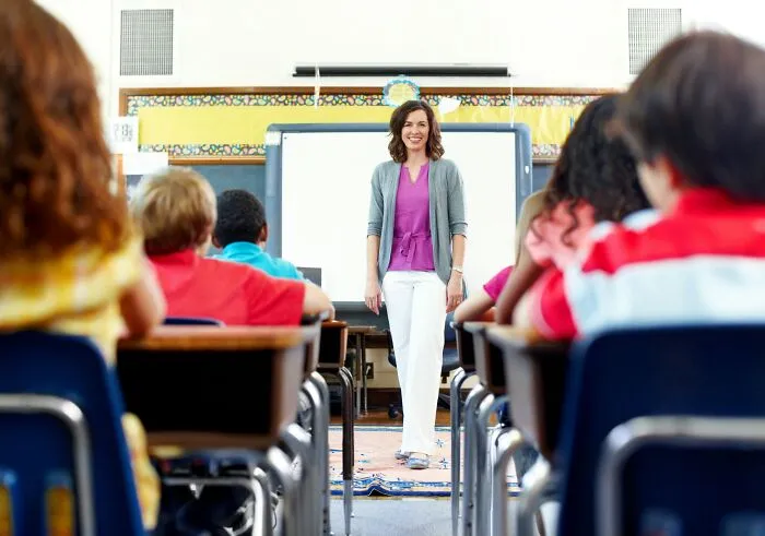 A teacher standing at the front of a classroom filled with elementary students in a tiny community